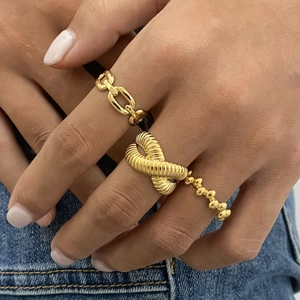 Primo piano di tre anelli d'oro in acciaio inossidabile con design a catena e spirale