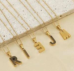 Détail des colliers alphabet plaqué or 18 carats R I E J M avec accents en émail noir
