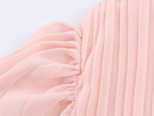 Detailed macro view of the elegant pink pleated chiffon fabric on the bell sleeve dress