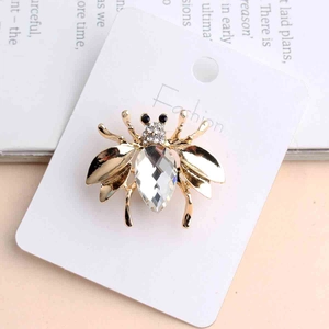 Macro detail of bee insect brooch with large crystal drop and diamond-encrusted body