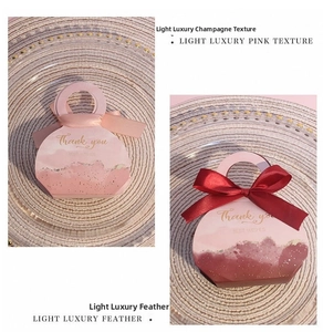Detail of pink and burgundy handbag-style wedding candy boxes with silk bow ribbons