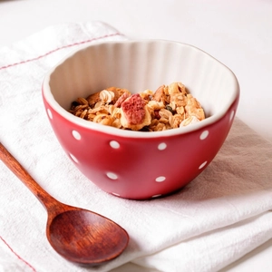 Close-up of a red mushroom ceramic bowl with white polka dots filled with fresh oatmeal