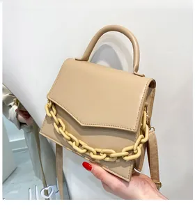 Detail of light coffee shoulder bag with chunky chain decor and adjustable strap
