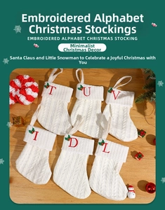 Close-up of cable knit Christmas stockings with red embroidered letters and holly leaves