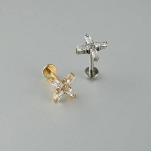 Vue détaillée de clous d'oreilles en titane en forme de croix dorés et argentés avec cristal