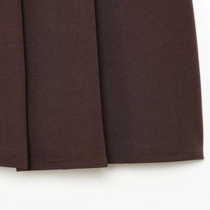 Jupe plissée marron foncé longueur genou avec texture en sergé et détails de l'ourlet