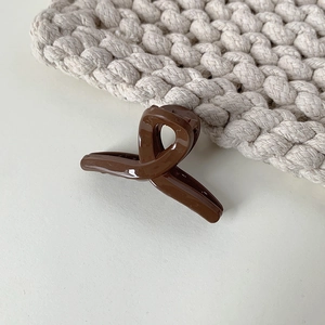 Detailed close-up of a dark coffee glossy mini hair claw clip with a twisted design