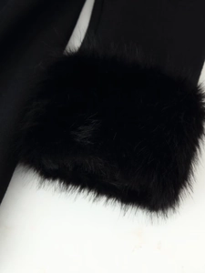 Détail du revers de manche en fausse fourrure noire sur un manteau long en laine douce