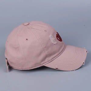 Détails de la casquette rose délavée avec broderie cœur rouge et finitions usées