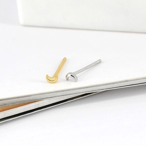 Detailed close-up of crescent moon stud earrings in polished gold and silver finishes