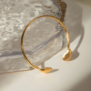 Elegant 18k gold plated stainless steel open bangle with scallop shell charms on beige background