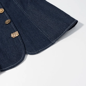 Détail du denim bleu foncé avec boutons métalliques dorés martelés et surpiqûres blanches