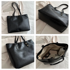 Detail of black leather tote bag showing large capacity, pebble texture, and reinforced straps