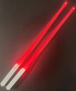 Close-up of dual glowing red LED chopsticks with white handles against dark background