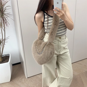 Detail view of khaki heart-shaped plush crossbody bag with silver chain and furry strap