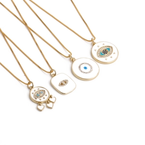 Macro detail of four gold-plated evil eye necklaces with cubic zirconia and blue enamel charms