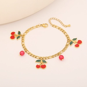 Détail d'un collier doré à double couche avec pendentifs cerises et perles rouges