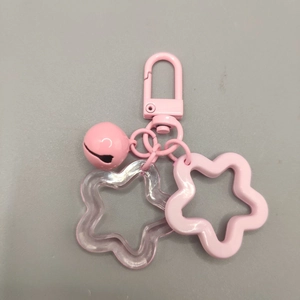 Close-up of pink star keychain with acrylic charms and a matching lacquered bell