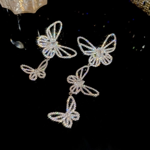 Macro shot of silver butterfly drop earrings with shimmering cubic zirconia on black base