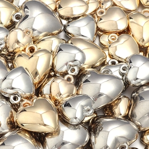 Macro shot of gold and silver heart-shaped CCB metallic pendants for DIY jewelry crafting