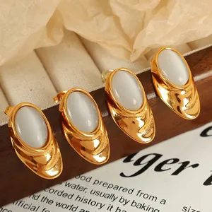 Retro 18k gold plated titanium steel earrings with white opal stones on dark wood background