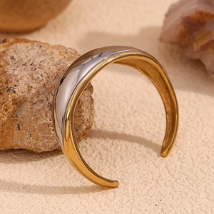 Macro shot of minimalist two-tone gold and silver plated stainless steel open bangle