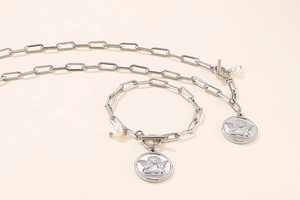 Detail of silver angel coin necklace and bracelet set with pearl and paperclip links