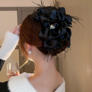 Vue détaillée arrière d'une pince à cheveux fleur en satin noir avec plumes et cristal