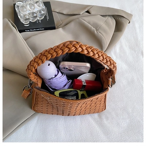 Internal storage view of brown woven handbag with umbrella, phone, and lipstick inside