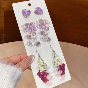 Detail of sweet floral and purple heart stud earrings set on a white card display