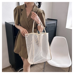 Detail showing the white mesh tote bag held by a model in an olive green dress