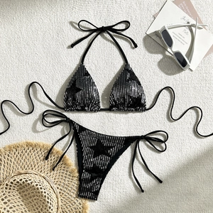 Detail shot of black two-piece bikini with silver sequins, sunglasses and straw hat