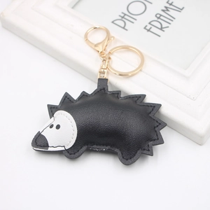 Detailed close-up of a black and white PU leather hedgehog keychain with gold hardware