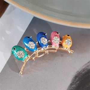 Close-up of enamel bird brooch with colorful crystals on golden branch detail