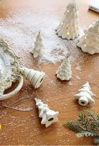 Detail of white ceramic Christmas tree ornaments with gold dots on a snowy surface