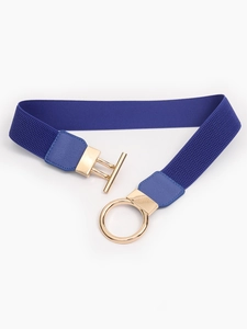Detail of navy blue elastic waist belt featuring a polished gold metal T-bar ring buckle