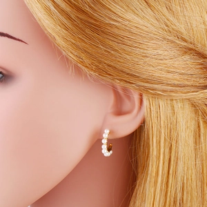 Elegant C-shaped earrings with white baroque pearls on a gold base worn by a model