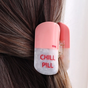 Detail of Chill Pill hair claw clip in pink and white acetate on brunette hair