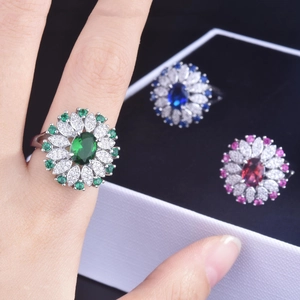 Close-up of floral gemstone rings featuring oval sapphire and emerald in silver settings