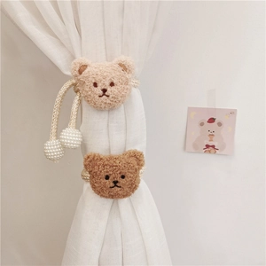 Detail of plush bear curtain tiebacks with pearl beads and woven rope on white curtains
