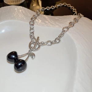 Detail of silver OT toggle necklace with black cherry pendants on textured tray