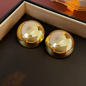 Close-up of a pair of minimalist golden dome stud earrings in a premium black jewelry box
