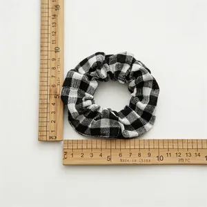 Elastic checkered scrunchie in black and white pattern with pleated fabric texture