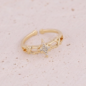 Macro shot of gold-plated open ring featuring a star pattern with cubic zirconia inlay