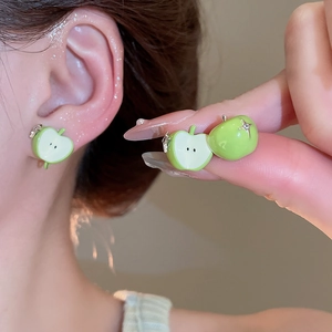 Detail of green apple earrings with cubic zirconia and enamel finish on model