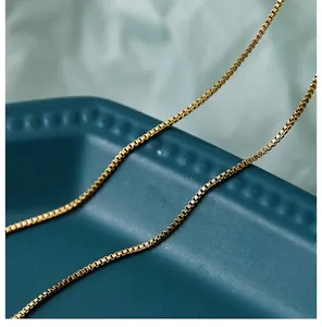 Macro shot of gold box chain necklace with dense square link structure on elegant display