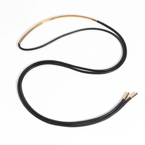 Detail of a minimalist gold metal tube necklace with black braided rope and tips