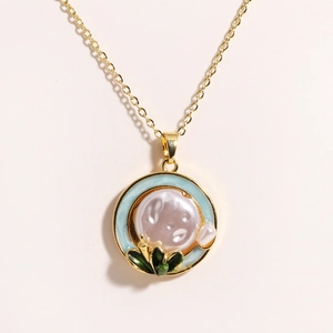 Detail view of gold flower pendant featuring light blue enamel and fresh water pearl