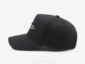 Side view of black cotton baseball cap showing white letter embroidery and ventilation eyelets