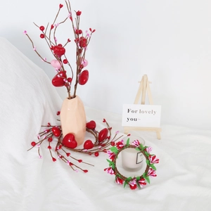 Detail of Valentine's day candle ring with red and pink heart berries and a ceramic vase